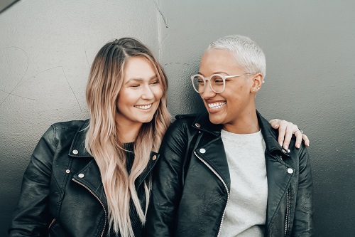 Two women wearing leather jackets with one wearing white rimmed glasses Two women wearing leather jackets with one wearing white rimmed glasses